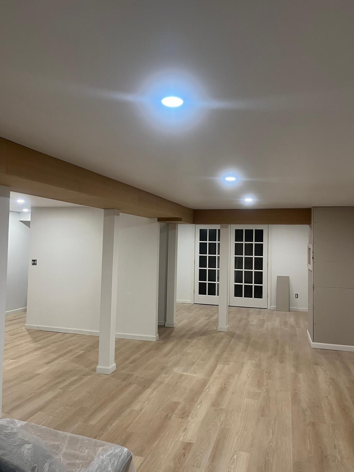 Finished basement with light flooring, white walls, and French doors